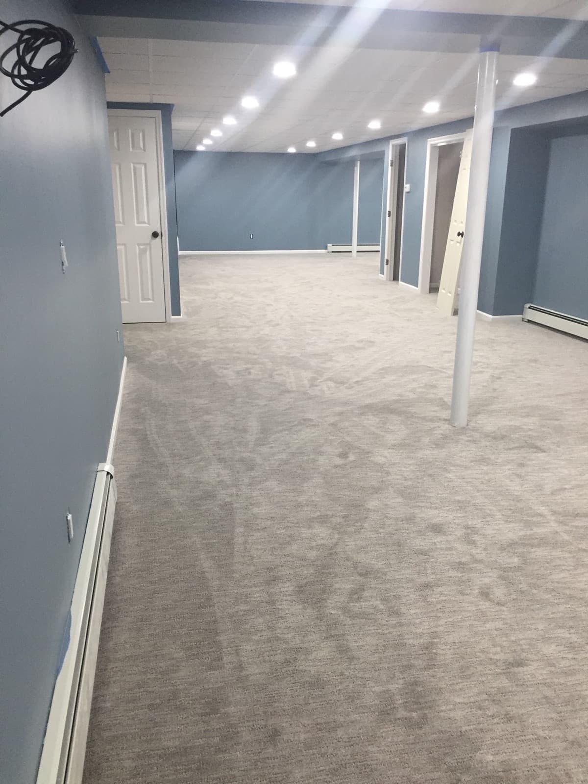 Finished basement showing painted walls, drop ceiling and new carpet