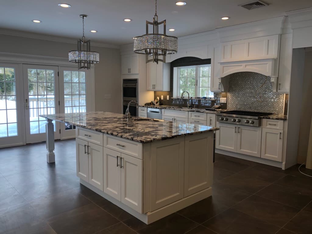 Wide view of the finished kitchen showing the island, range wall and french doors