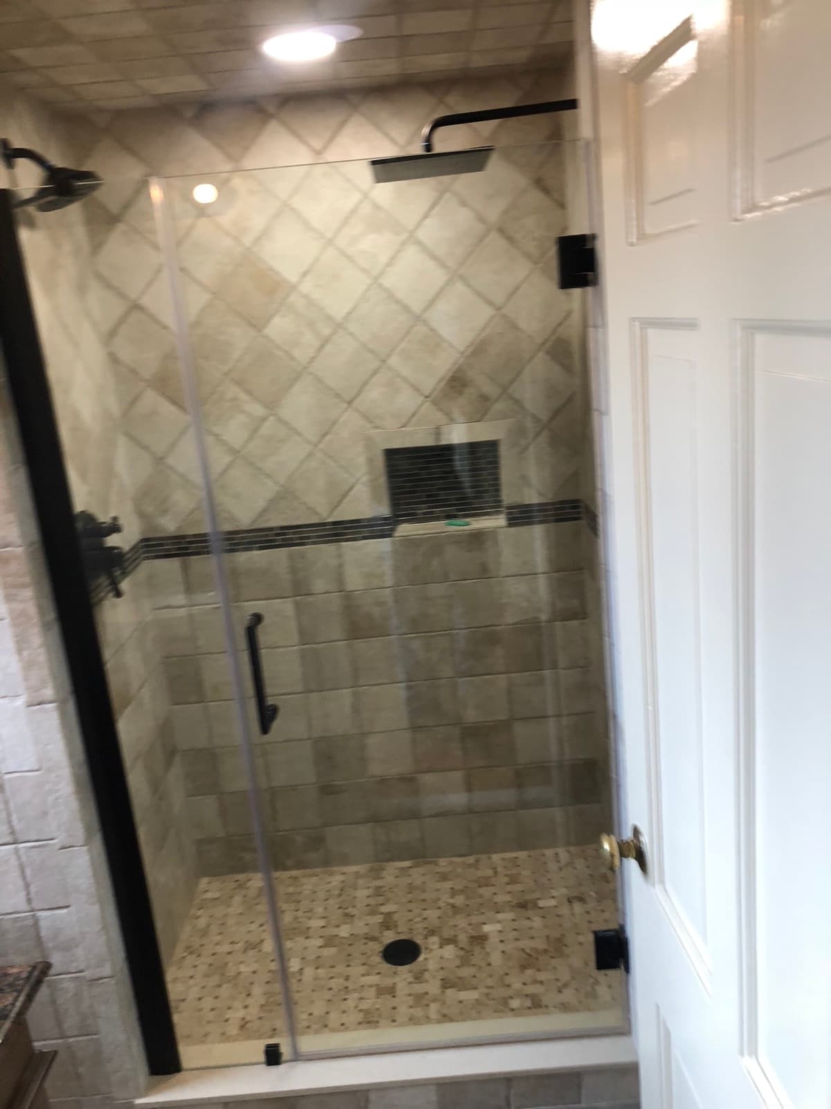 Tiled walk-in shower with a glass door, recessed niche and a tiled floor