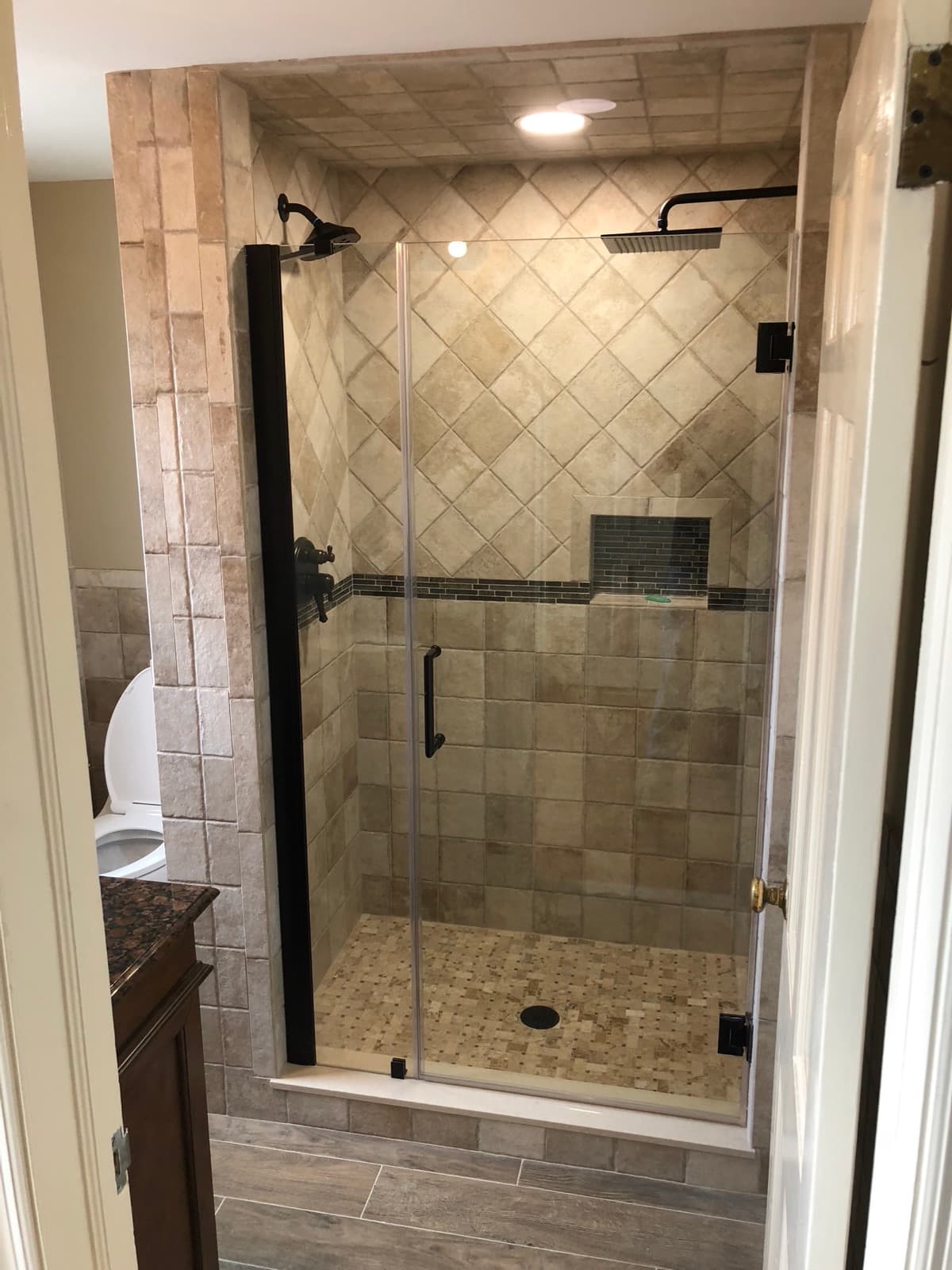 Tiled shower enclosure with a glass panel above the tub surround