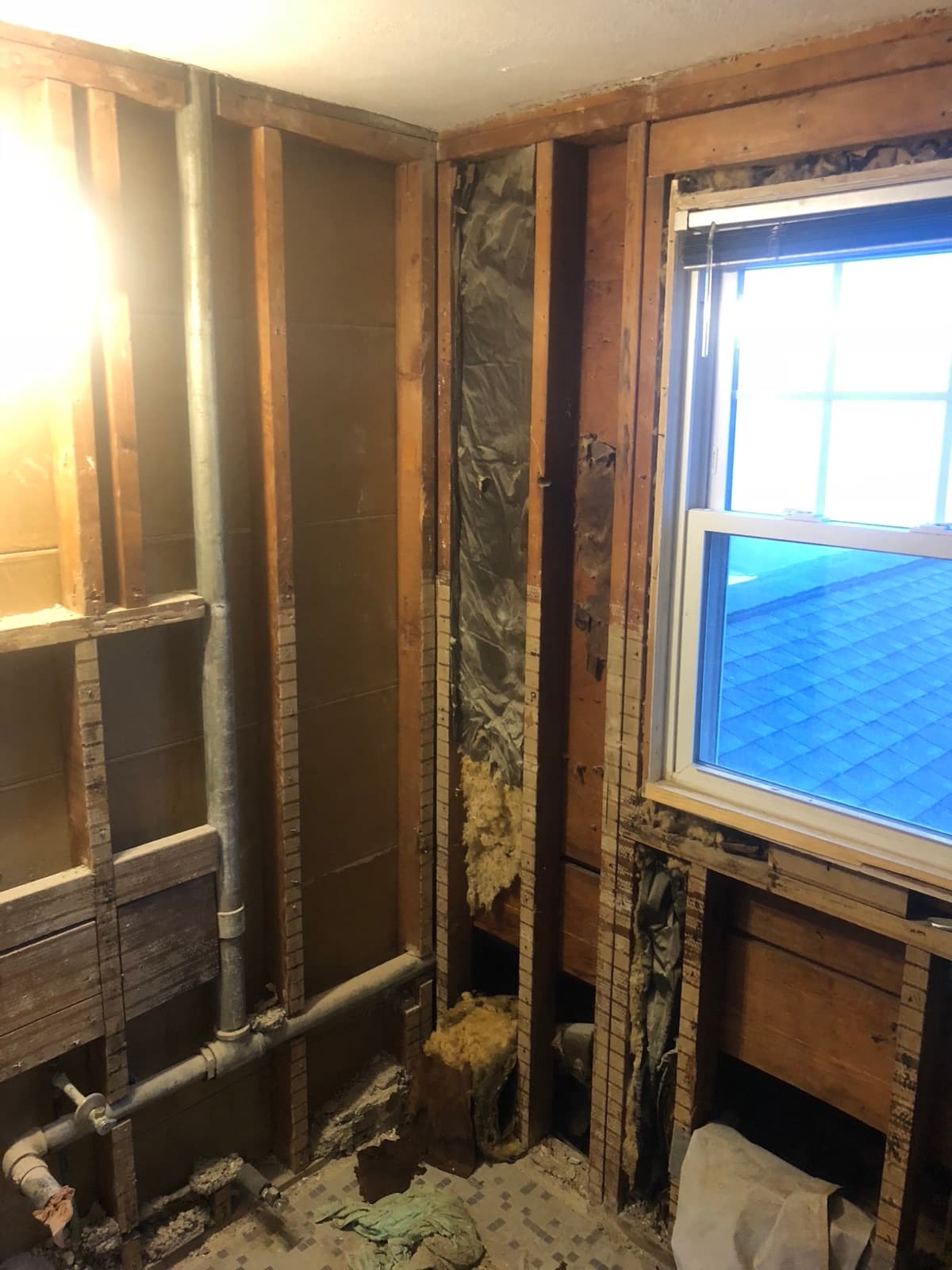The same bathroom stripped back to the studs with the old plumbing exposed