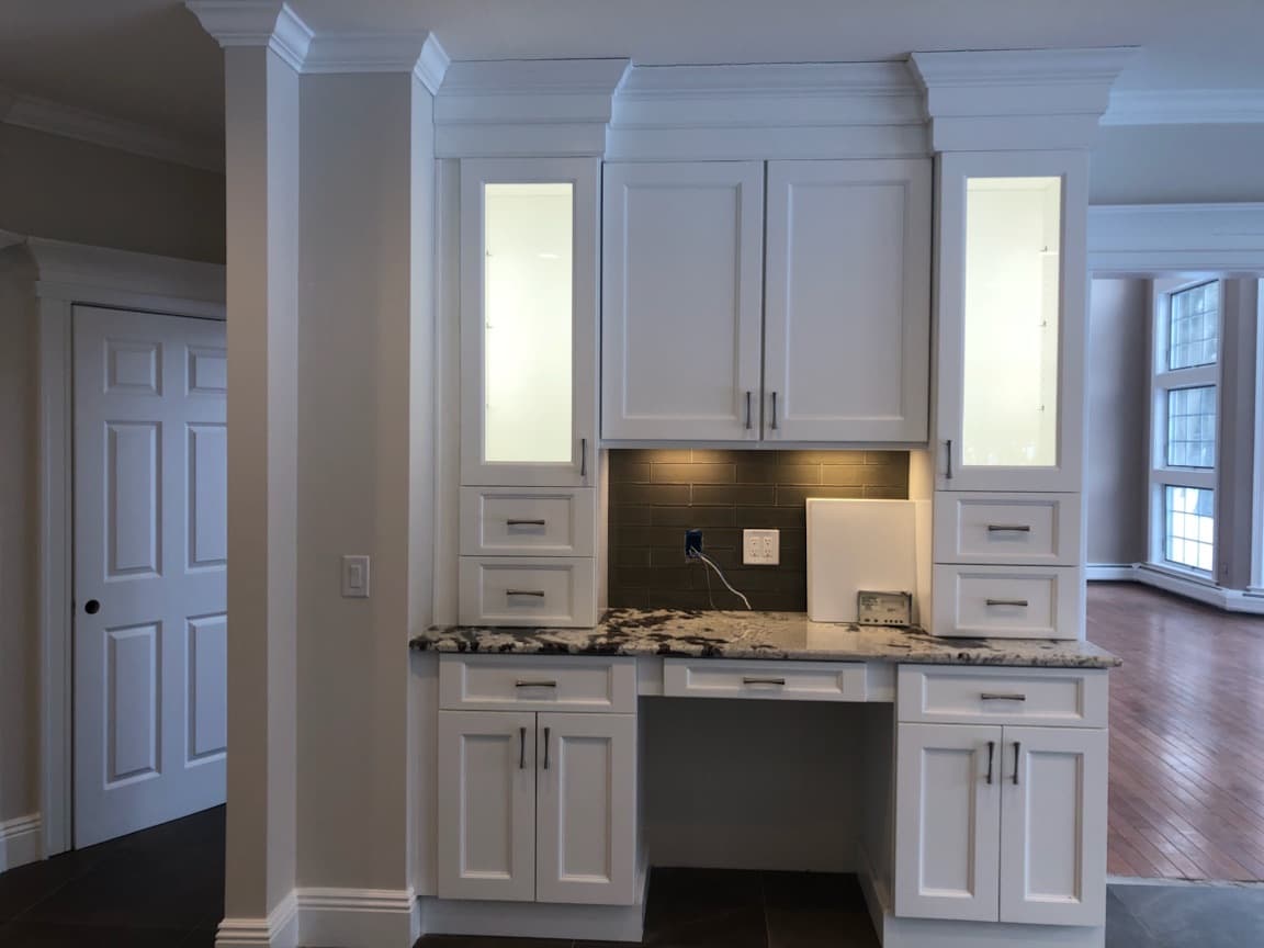 Built-in desk nook with granite top, glass display cabinets and tile backsplash
