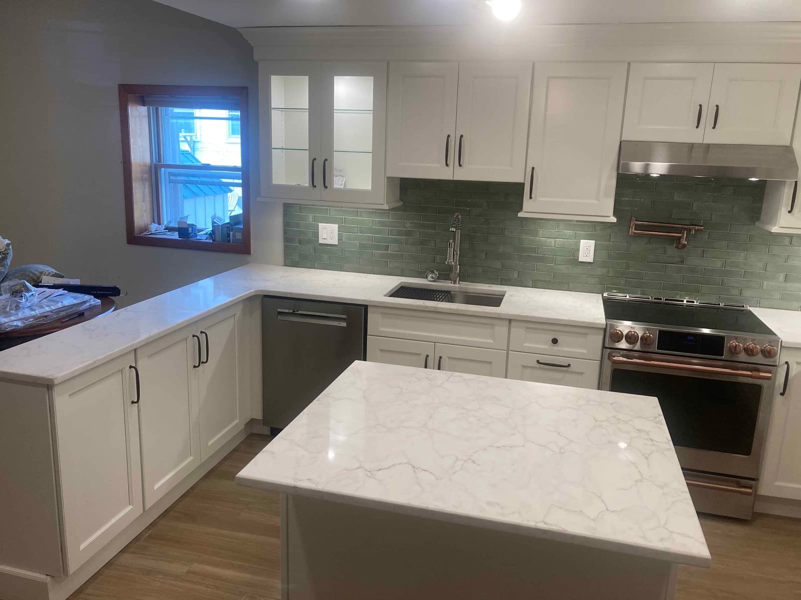Finished kitchen with white shaker cabinets, a green subway tile backsplash and a stone island