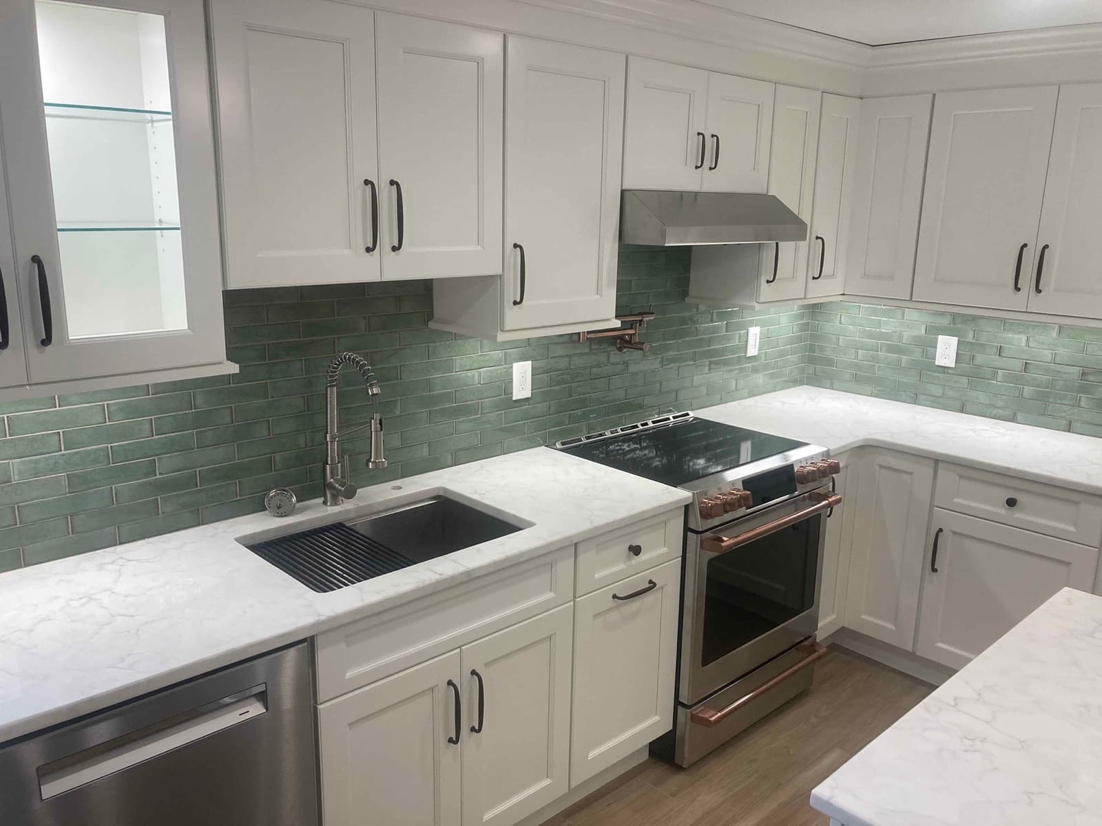 Kitchen sink run and slide-in range against a green subway tile backsplash