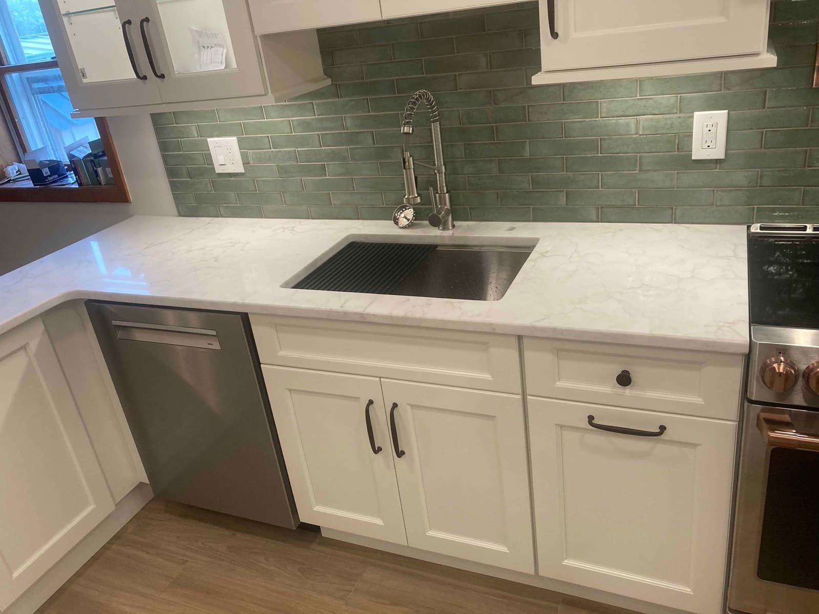 Undermount sink and dishwasher with green subway tile above the counter