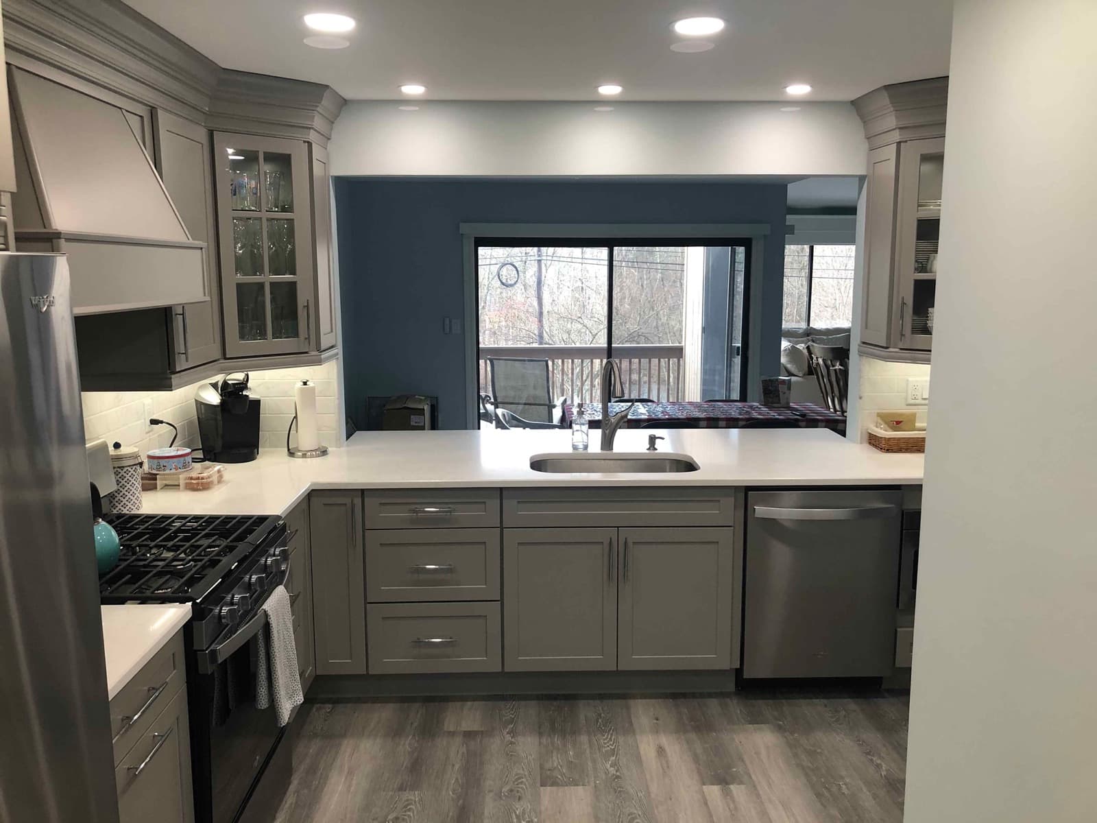 Grey shaker kitchen with white counters, a peninsula sink and sliding doors to a deck