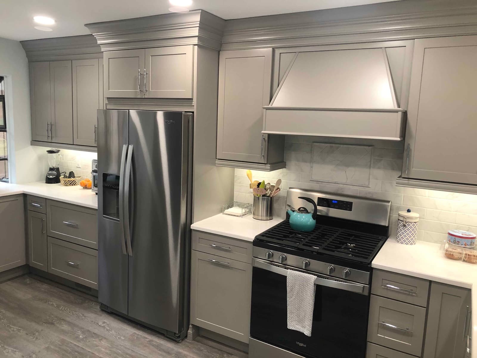Grey shaker cabinets with a built-in hood surround above a gas range
